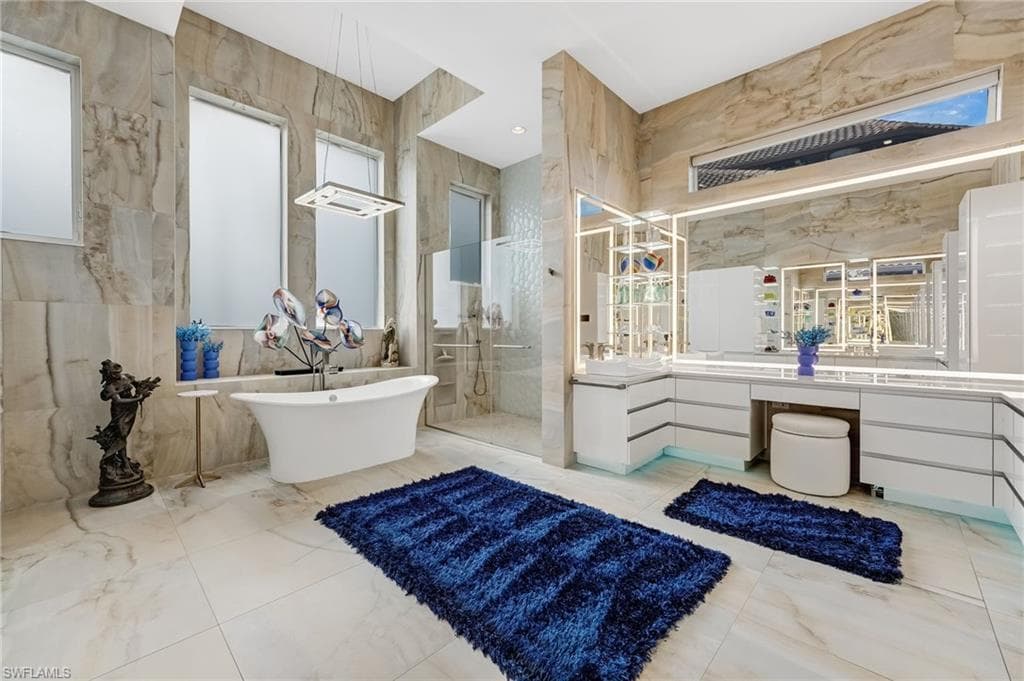 Designed as a private sanctuary, the oversized primary ensuite boasts backlit mirrors with a built-in television, a heated towel rack, porcelain-clad walls, a spacious walk-in shower, and a refined freestanding soaking tub.
