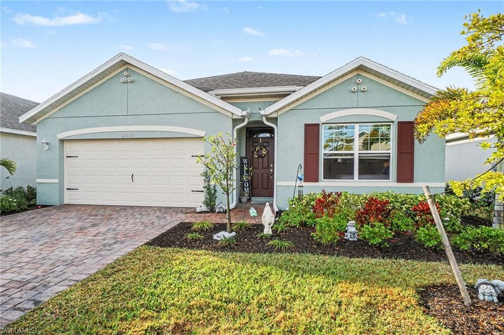 Ranch-style house with stucco siding, an attached garage, driveway, and roof with shingles