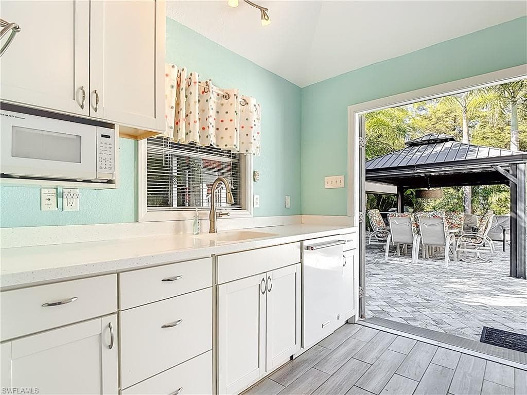 Kitchen with white appliances, white cabinets, and wood finish floors