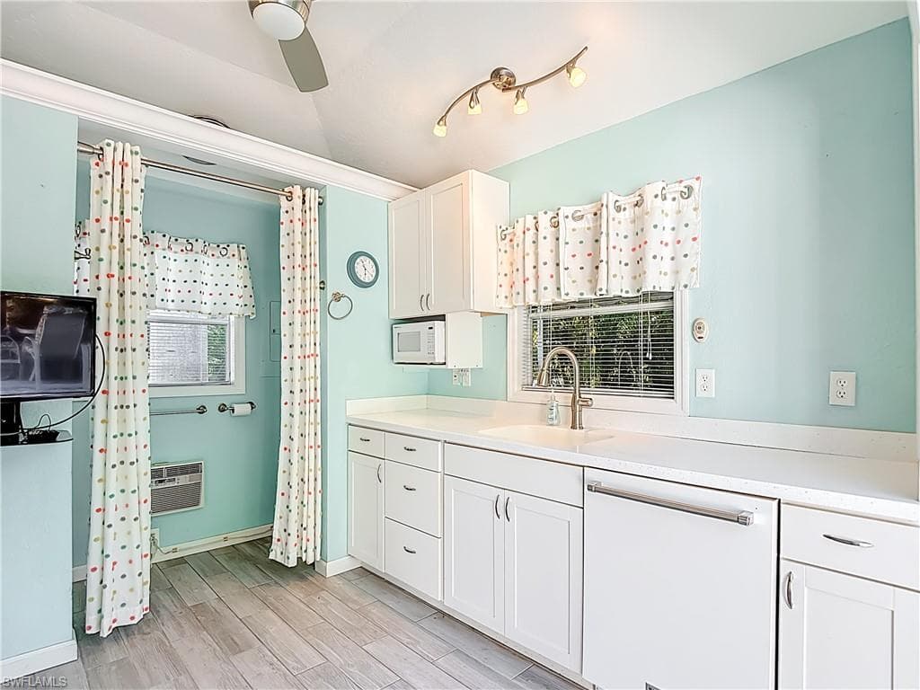 Kitchen with white cabinets, white appliances, light countertops, a ceiling fan, and lofted ceiling