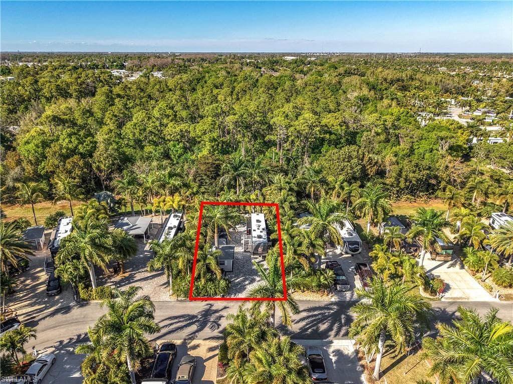Aerial view of property and surrounding area featuring property parcel outlined and a forest