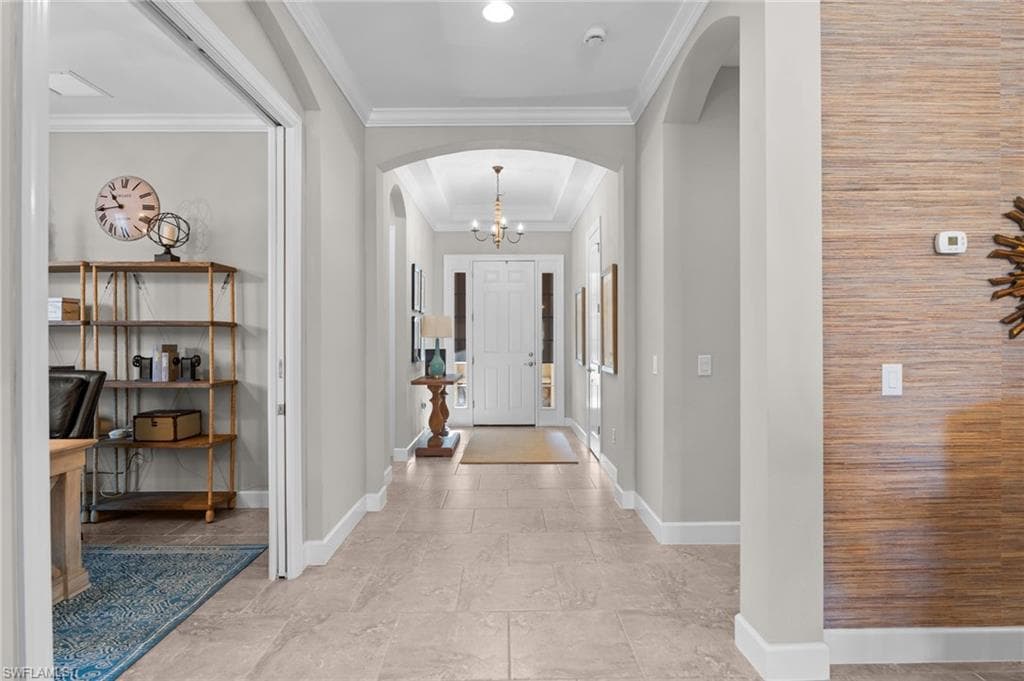 Entryway with arched walkways, crown molding, and suspended lighting