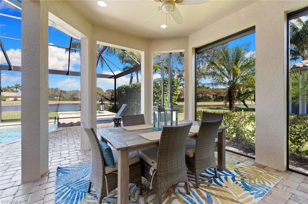 Sunroom / solarium with ceiling fan, a patio, outdoor dining area, and a water view