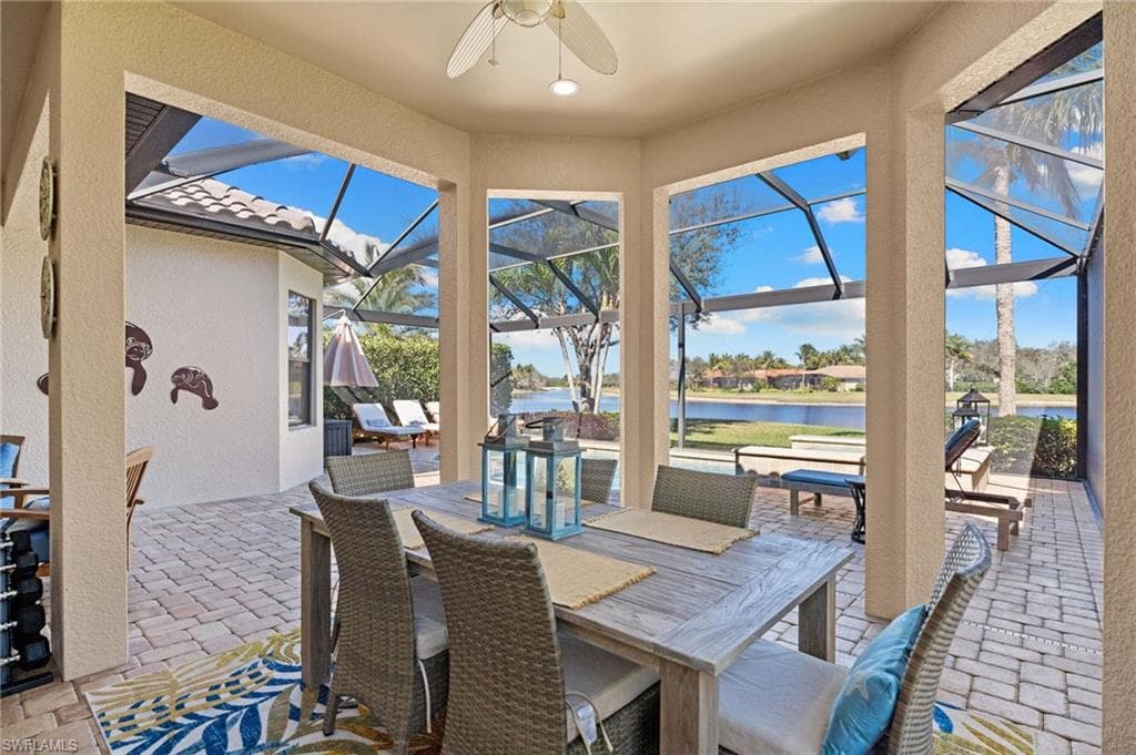 View of patio featuring a sunroom, ceiling fan, a lanai, outdoor dining area, and a water view