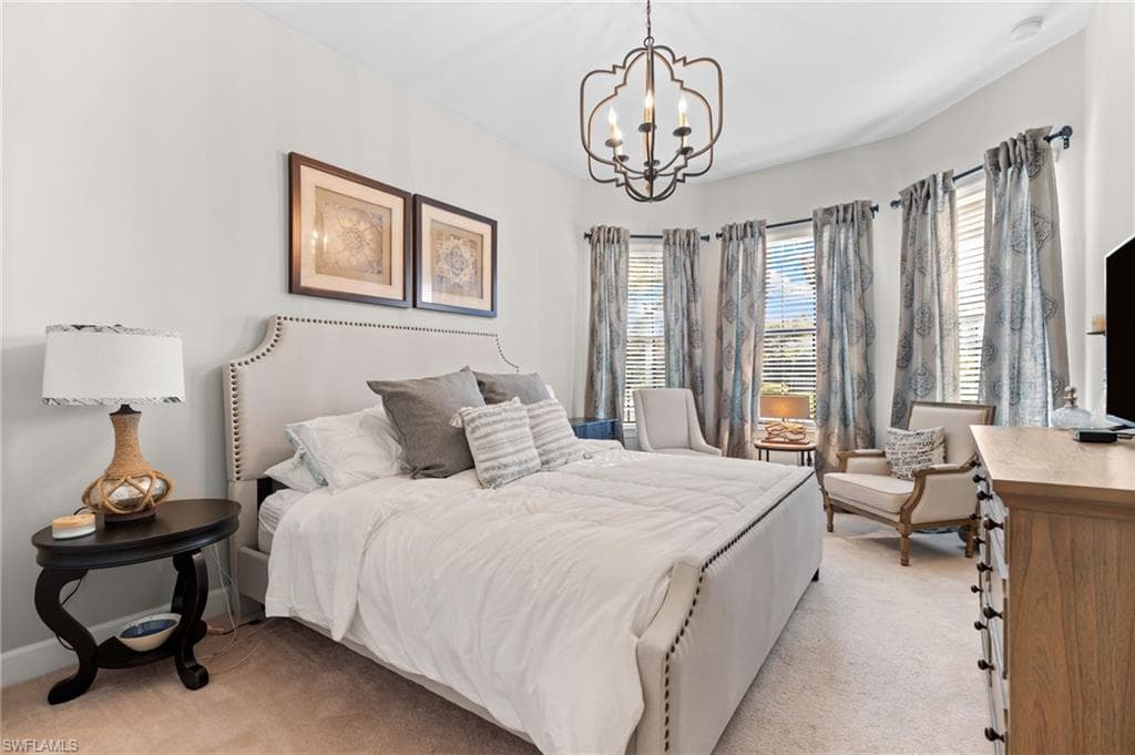 Bedroom featuring light colored carpet and a chandelier
