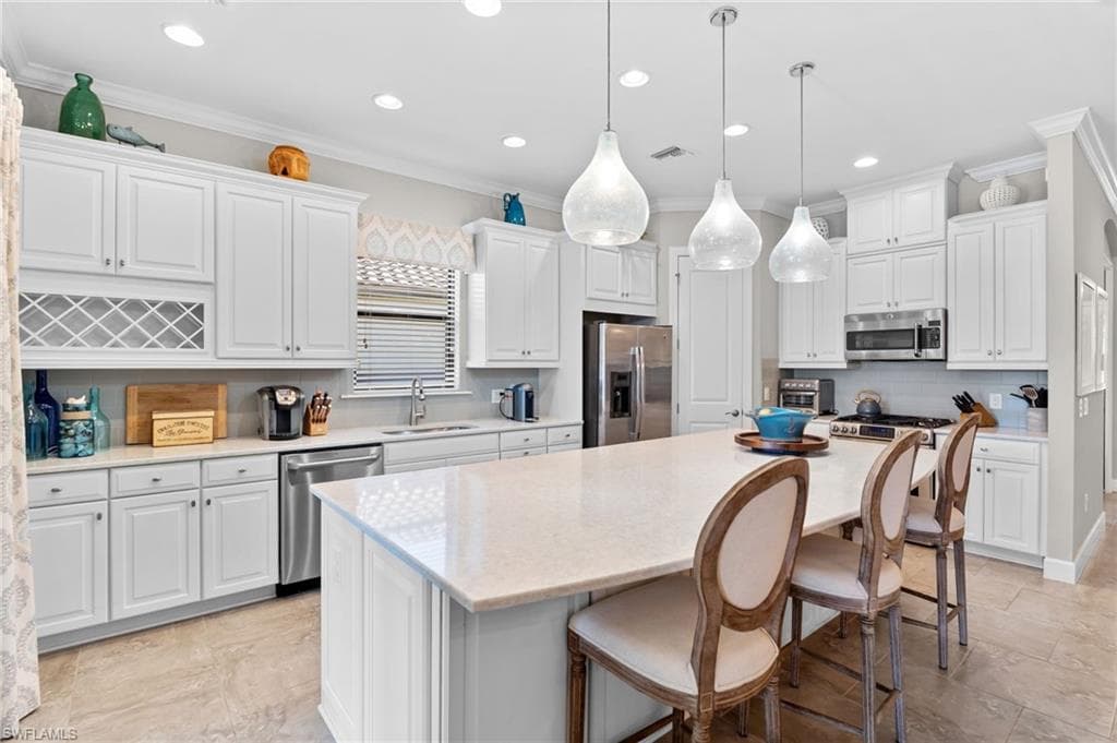 Kitchen with a breakfast bar, stainless steel appliances, a center island, tasteful backsplash, and white cabinetry