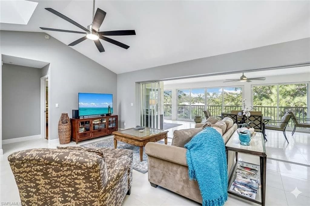 Open-concept living space featuring vaulted ceilings, light gray walls, and large format tile flooring
