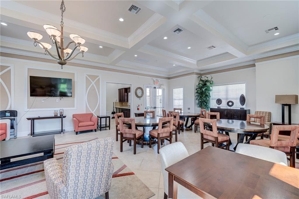 Dining space with hanging lights, ornamental molding, coffered ceiling, and light tile patterned flooring