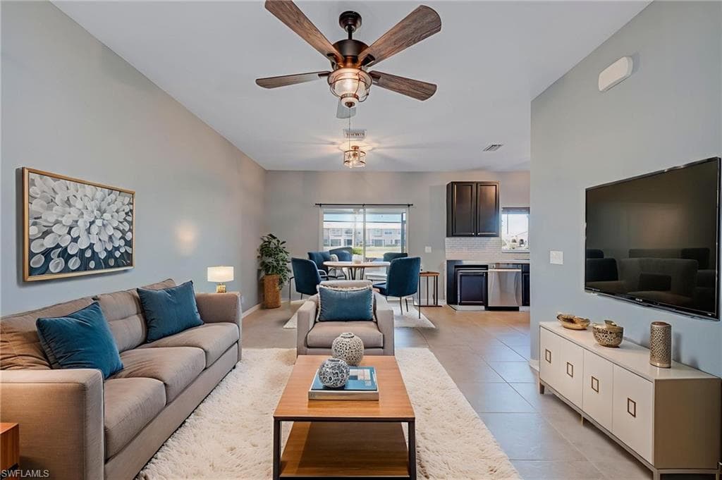 Living room featuring a ceiling fan, light tile patterned floors, and lofted ceiling
