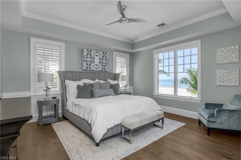Bedroom with hardwood / wood-style floors, ceiling fan, ornamental molding, and a water view