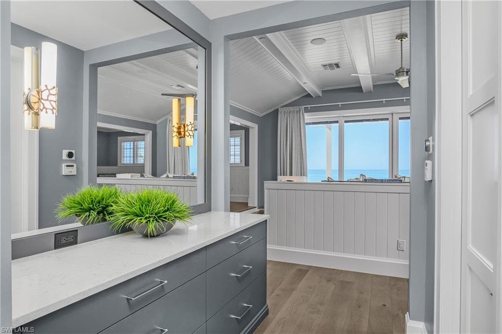 Bathroom with lofted ceiling with beams, dark wood-style floors, vanity, a ceiling fan, and a water view