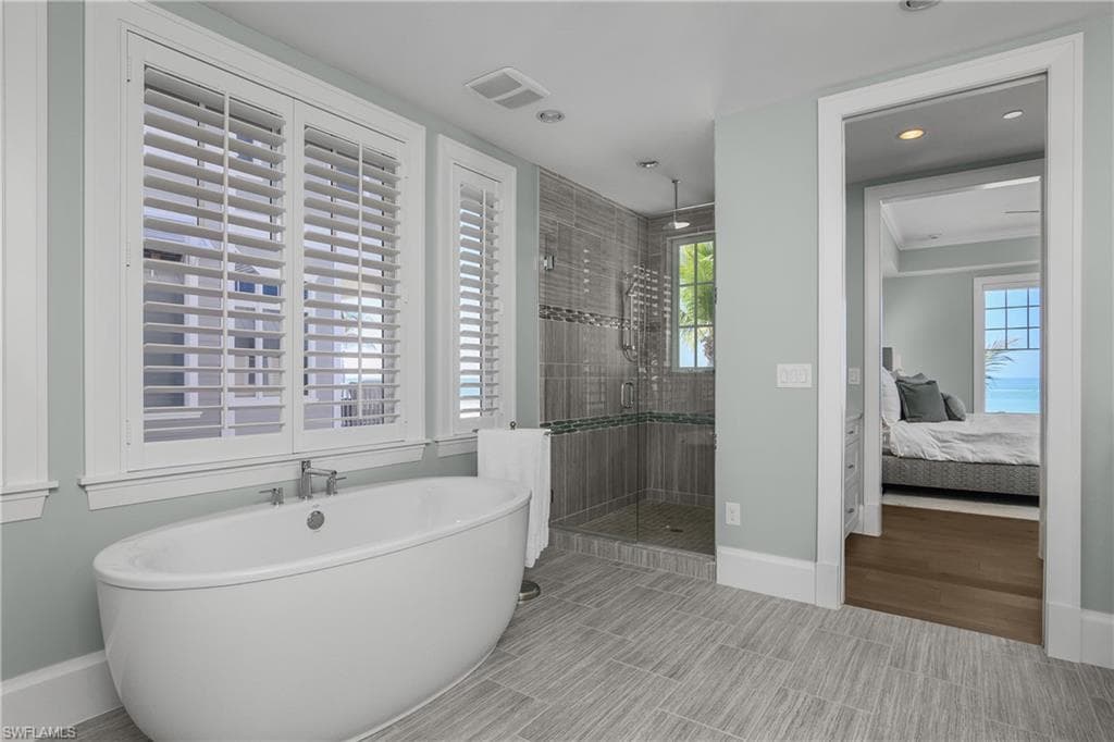 Full bath with connected bathroom, a stall shower, a freestanding bath, and recessed lighting