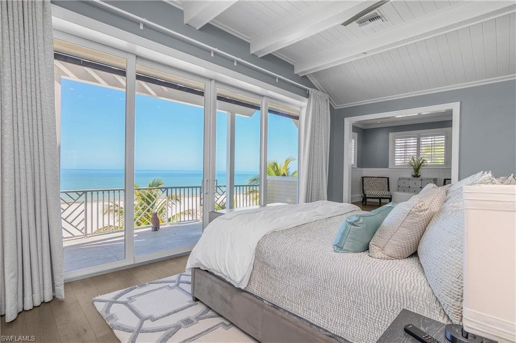 Bedroom featuring a water view, lofted ceiling with beams, access to outside, hardwood / wood-style flooring, and wooden ceiling