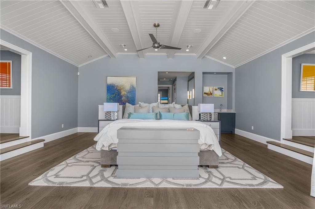 Bedroom featuring dark wood-style flooring, wainscoting, and beam ceiling