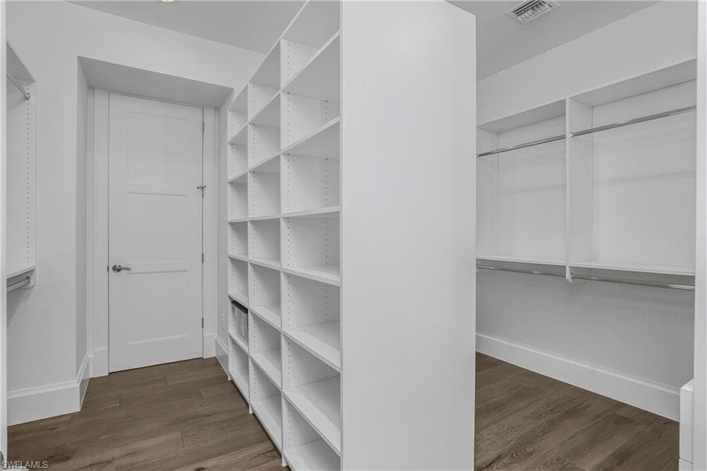 Walk in closet with dark wood finished floors