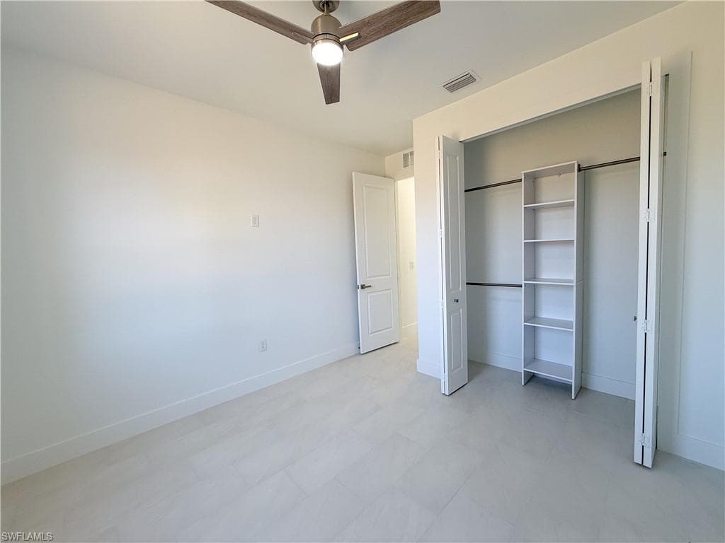 Unfurnished bedroom featuring light flooring, a ceiling fan, and a closet