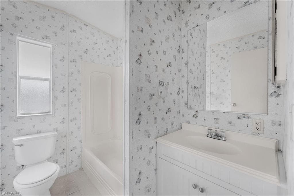 Full bathroom with vanity, light tile patterned floors, and washtub / shower combination