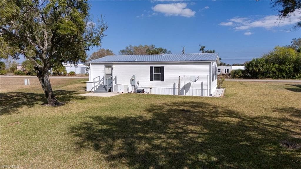 Rear view of property featuring a yard and a metal roof