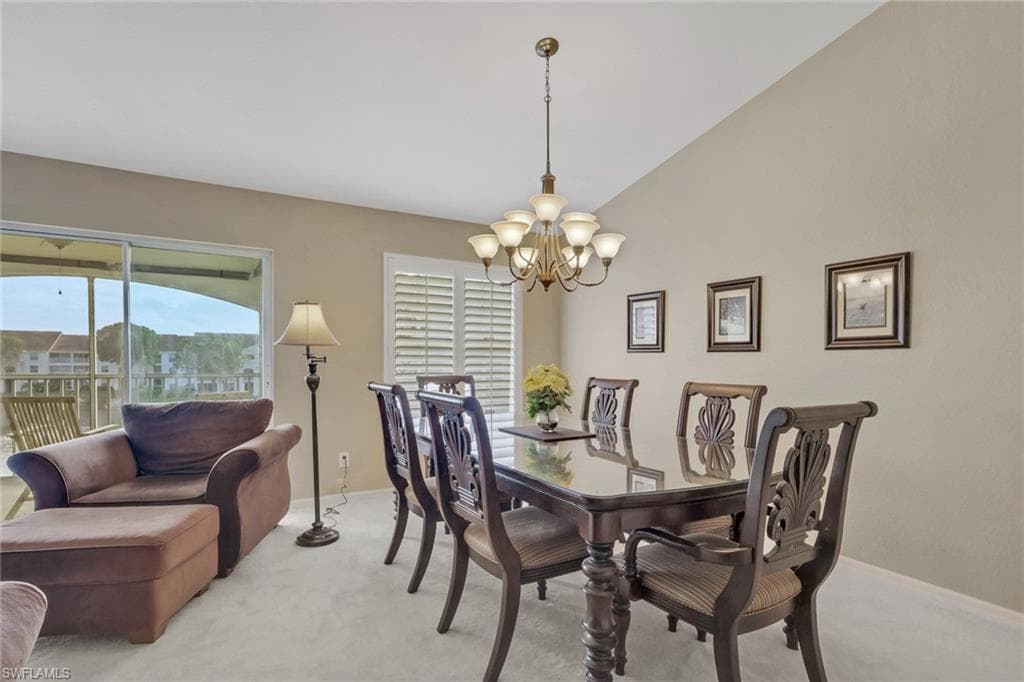 Dining space featuring a chandelier, plantation shutters, vaulted ceiling, and plenty of natural light with lake view