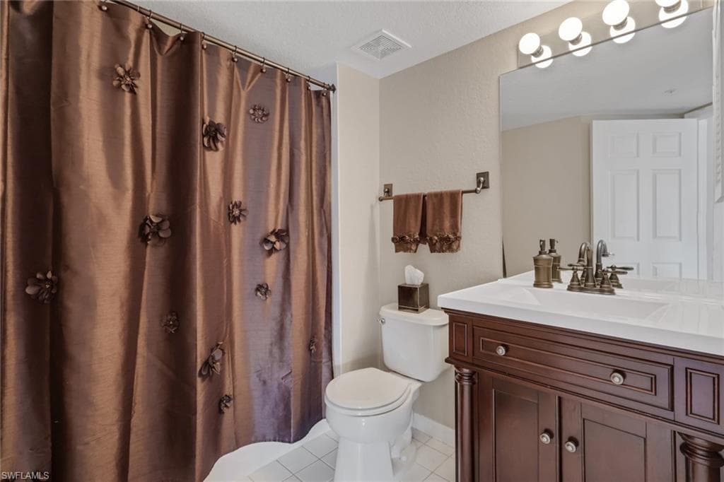 Bathroom with curtained shower, vanity, and light tile patterned floors
