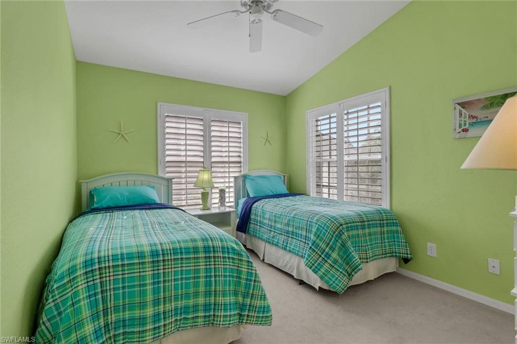 Bedroom with plantation shutters, lake view, light carpet, and ceiling fan