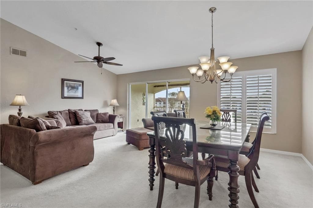 Dining space with lofted ceiling, hanging lights, light carpet, and a ceiling fan