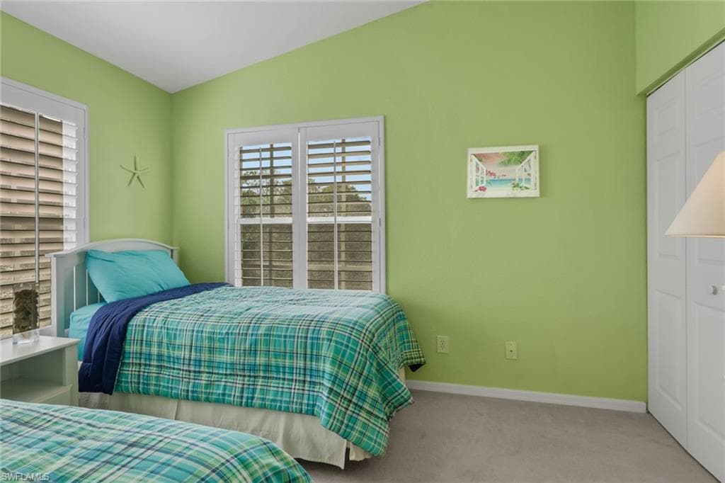 Carpeted bedroom featuring a walk in closet and plantation shutters