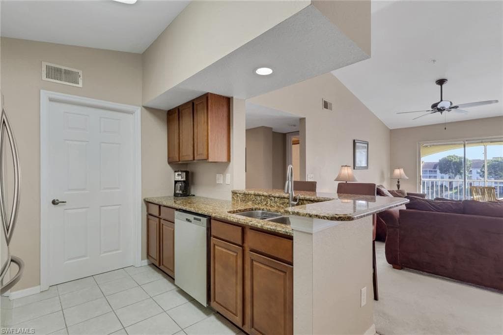 Kitchen featuring lofted ceiling, granite counters, wood finish cabinetry, a peninsula, and open floor plan