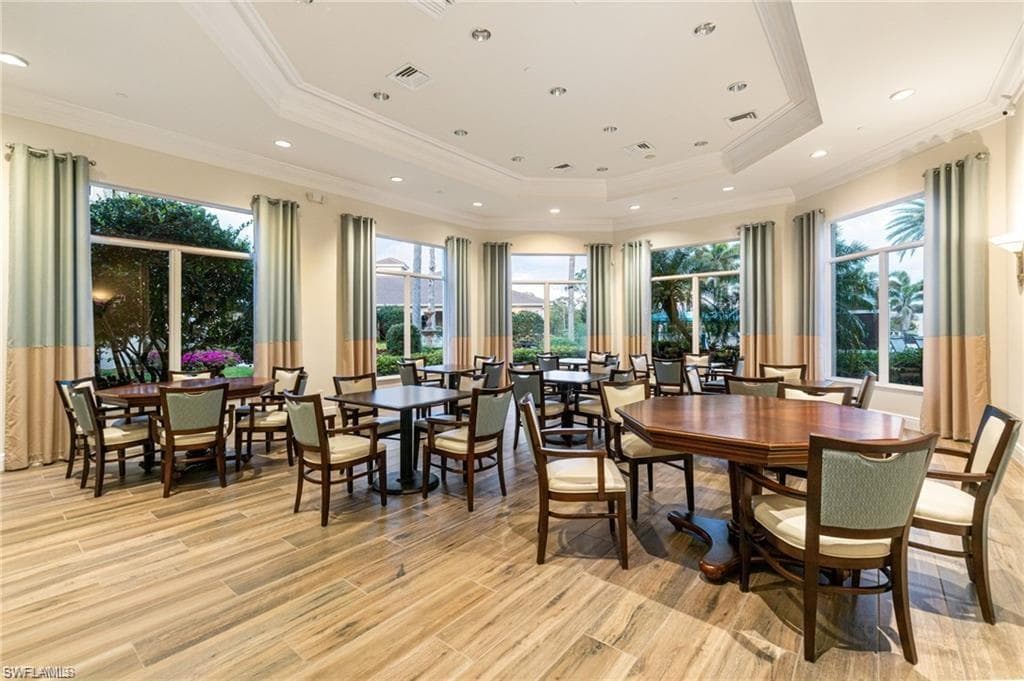 Dining space with a tray ceiling, light wood-style floors, crown molding, and recessed lighting