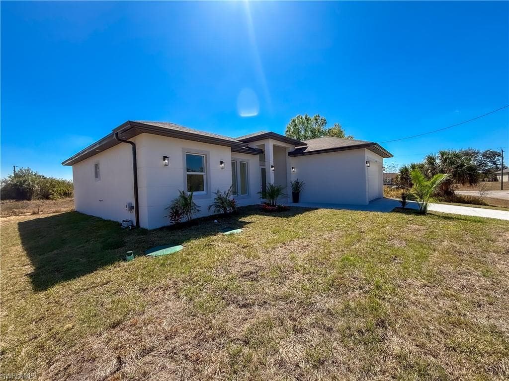 Single story home featuring a front lawn, a garage, and stucco siding