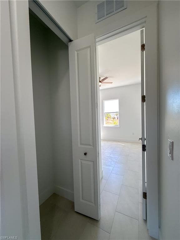 Hallway closet with baseboards and light tile patterned floors