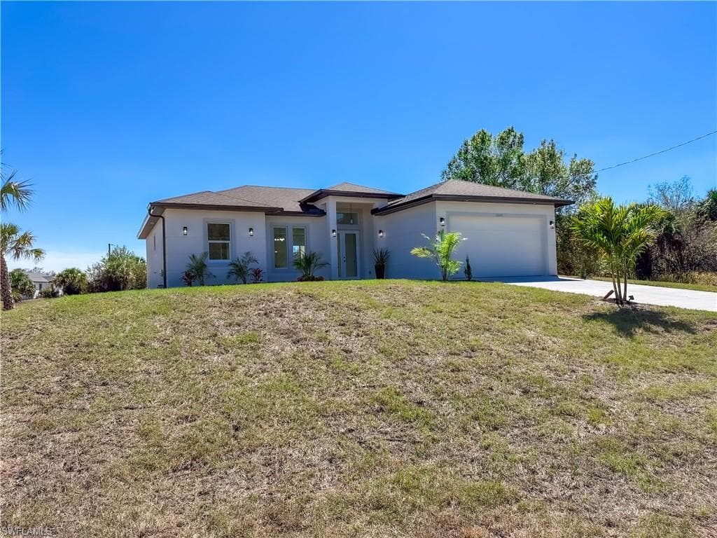 View of front of property with a front yard, stucco siding, an attached garage, and concrete driveway