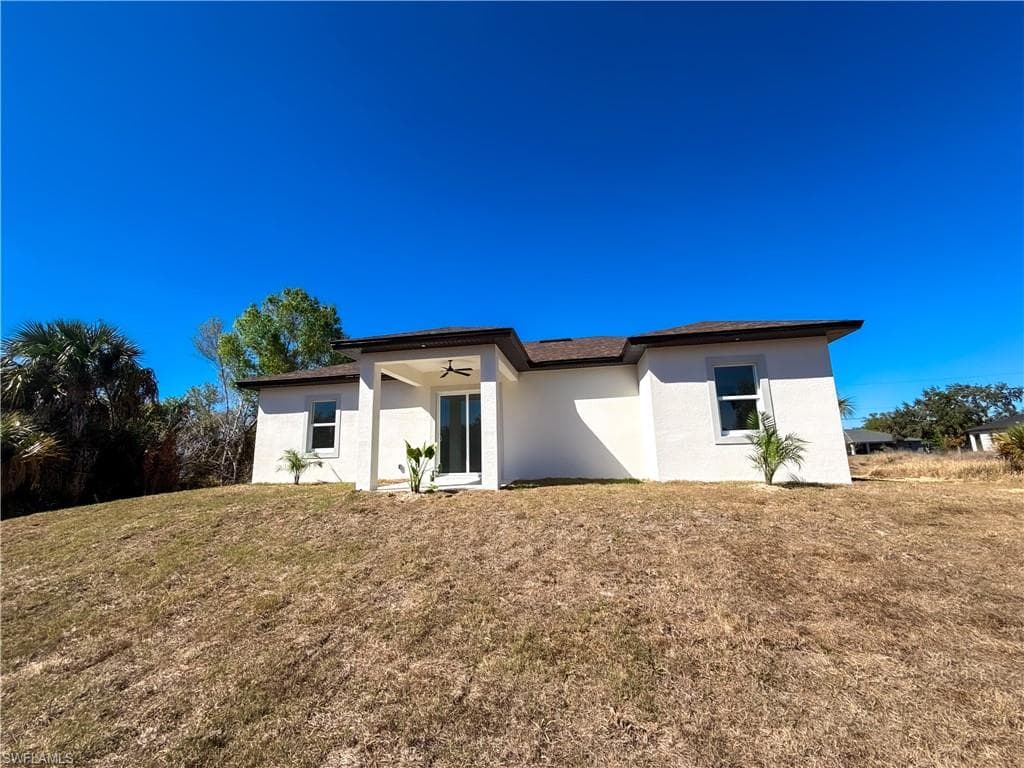 Back of house featuring stucco siding and a lawn
