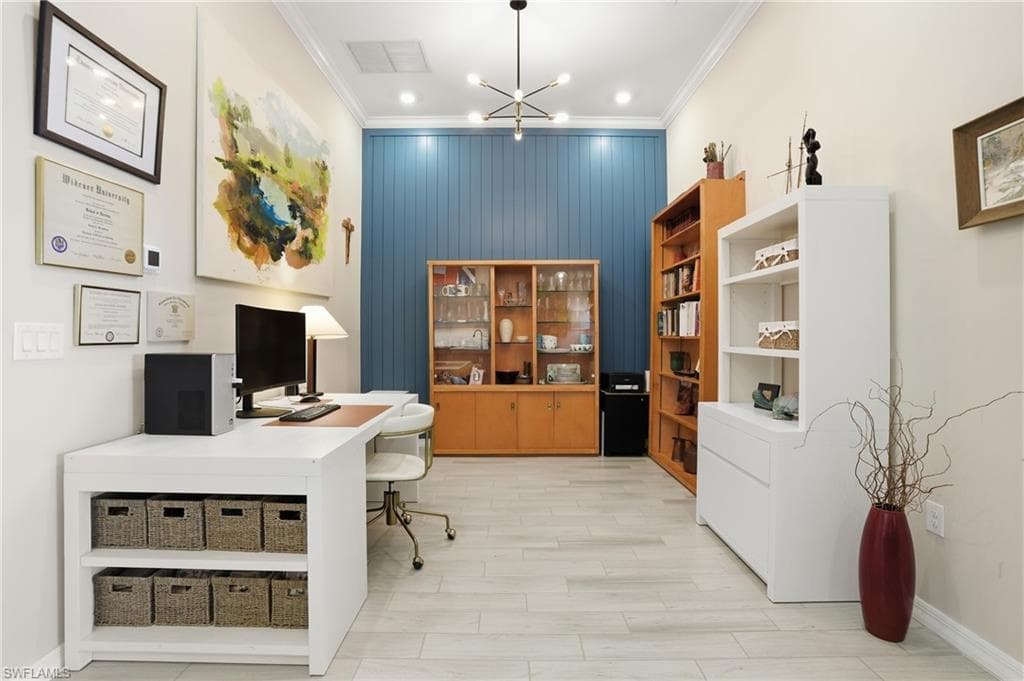 Office space featuring hanging lights, crown molding, wood finish floors, and an accent wall
