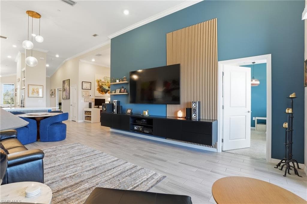 Living area featuring light wood-style flooring, ornamental molding, and lofted ceiling