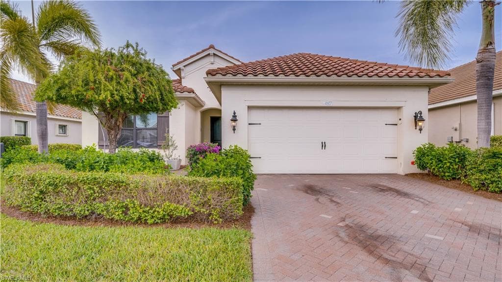 Mediterranean / spanish home featuring decorative driveway, an attached garage, and stucco siding
