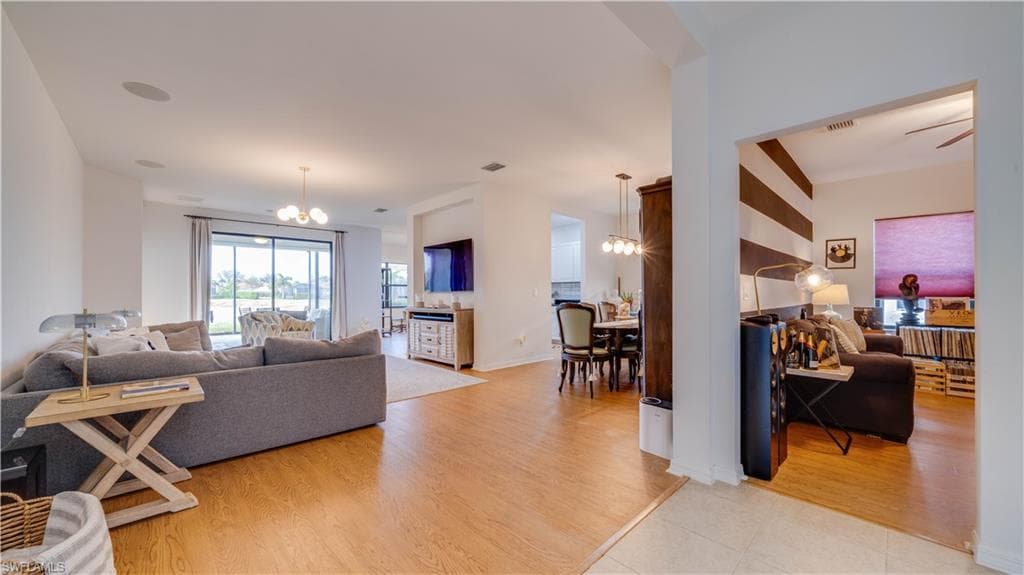 Living room with suspended lighting and light wood-type flooring