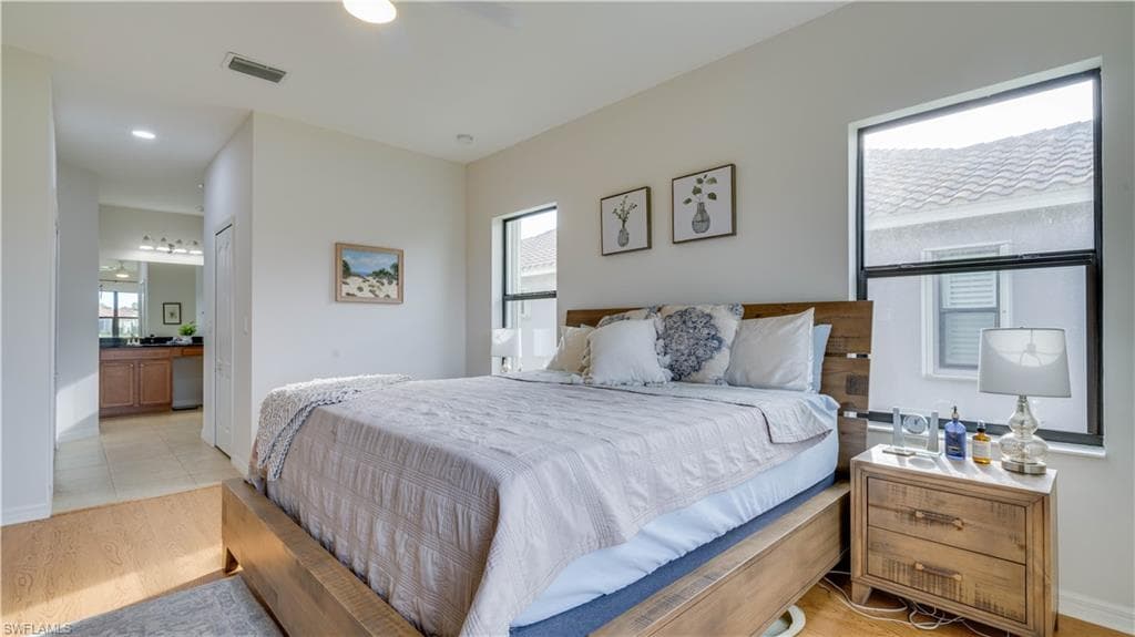 Bedroom featuring light wood-type flooring, a ceiling fan, and ensuite bathroom