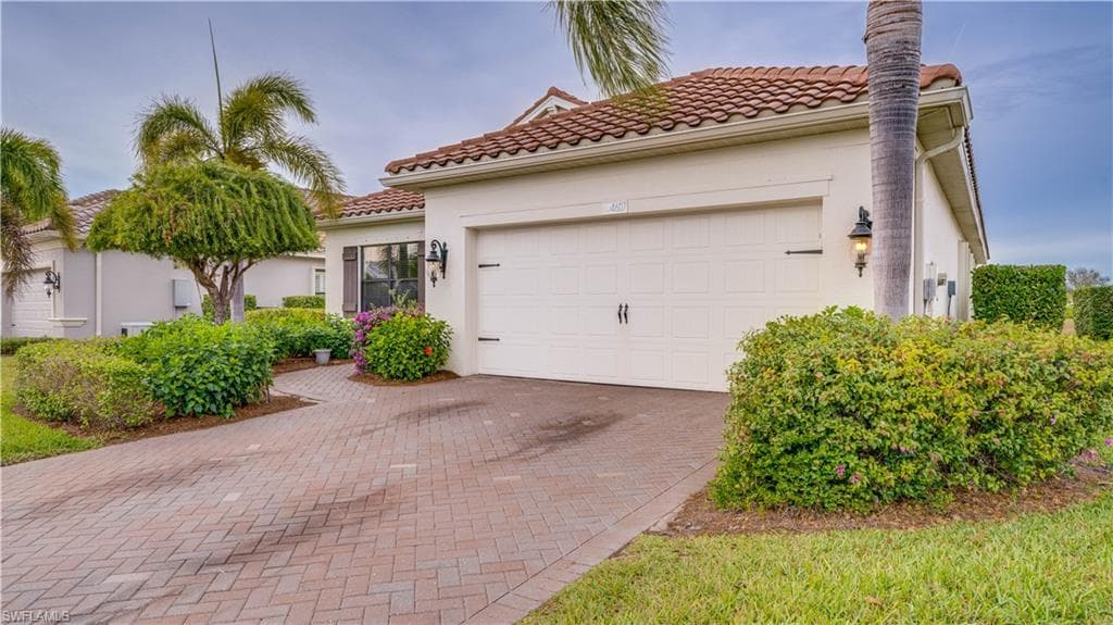 Mediterranean / spanish home with decorative driveway, a garage, stucco siding, and a tile roof