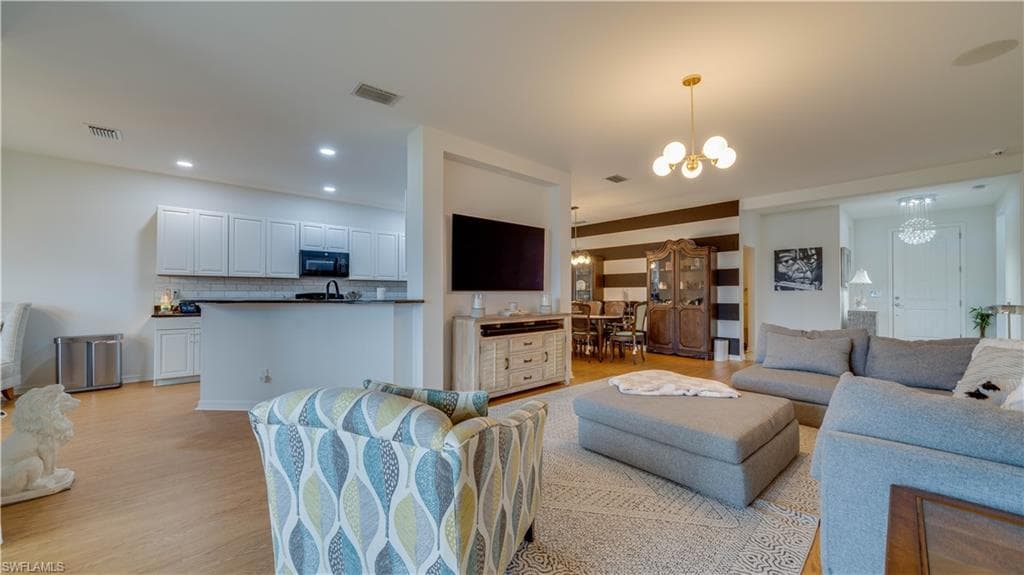 Living room with hanging lights and light wood-type flooring