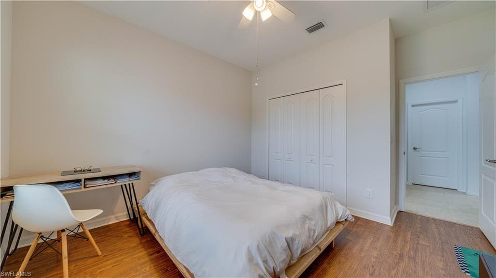 Bedroom featuring wood finished floors, a closet, ceiling fan, and a desk