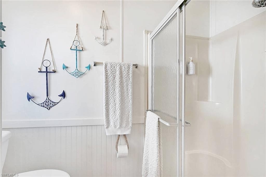 Full bath featuring a stall shower and a wainscoted wall