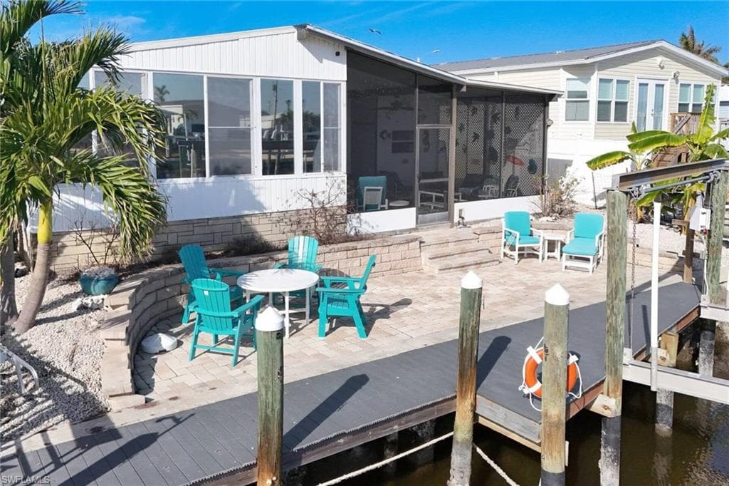 Rear view of property featuring outdoor dining space, a patio, and a sunroom