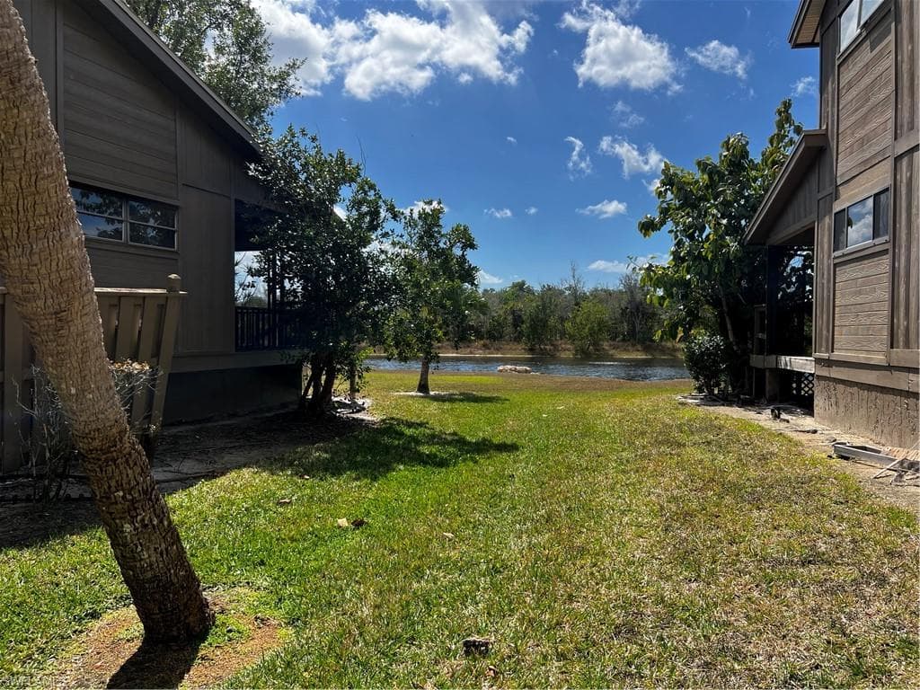 View of grassy yard featuring a deck with water view