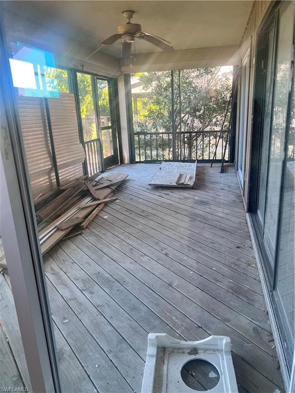 Unfurnished sunroom featuring a ceiling fan and a wooden deck