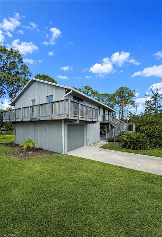 Back of house featuring a lawn, concrete driveway, an attached garage, and a balcony