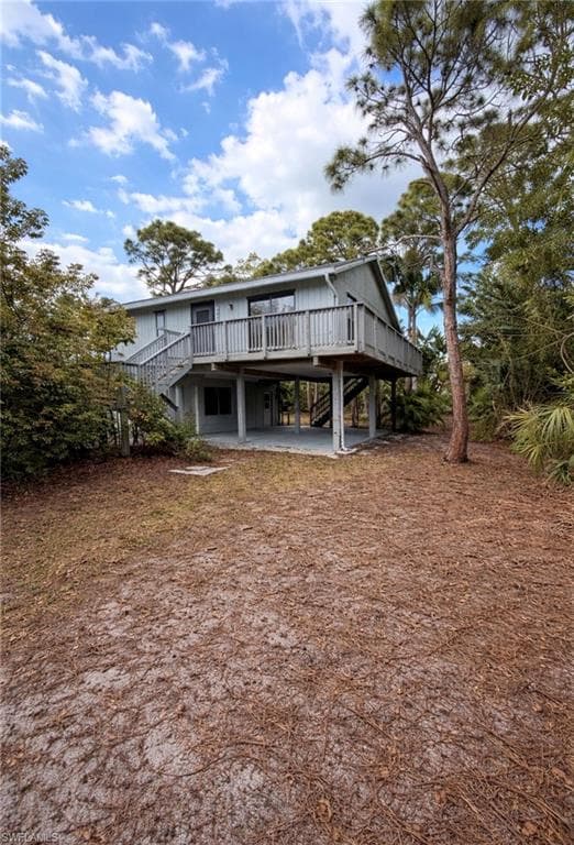 Rear view of property featuring a wooden deck, a patio, and a carport