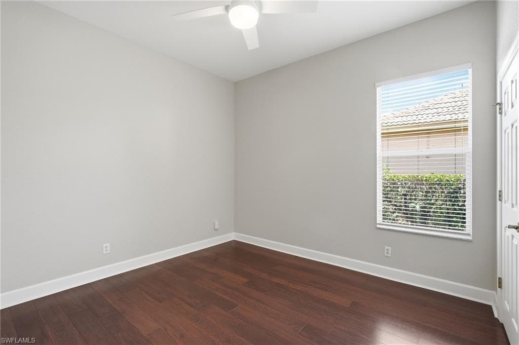 Neutral-toned room featuring rich wood-finish flooring and white baseboards