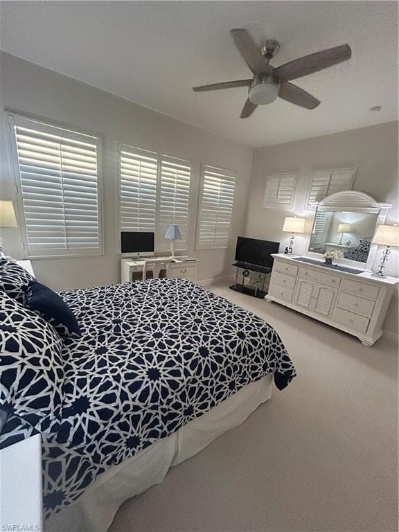 Bedroom featuring light carpet, a ceiling fan and custom plantation shutters