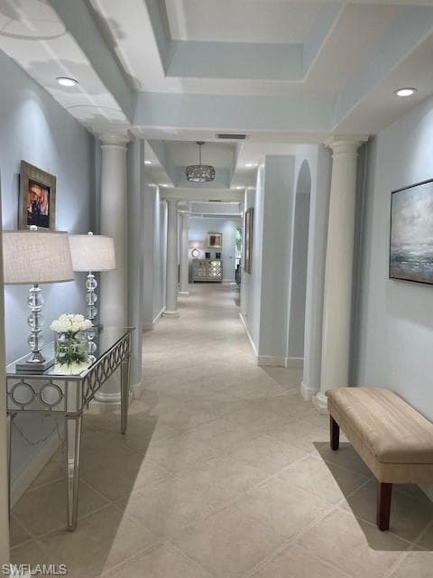 Hallway featuring decorative columns and light tile patterned floors